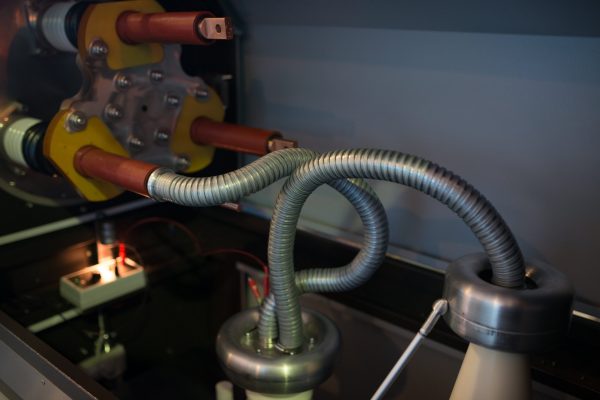 Three copper high voltage terminals with ceramic cylinders and connected high voltage conductor in test installation